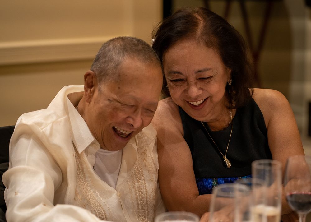 Two elderly people sharing a joyful laugh together at a formal dinner celebration event.
