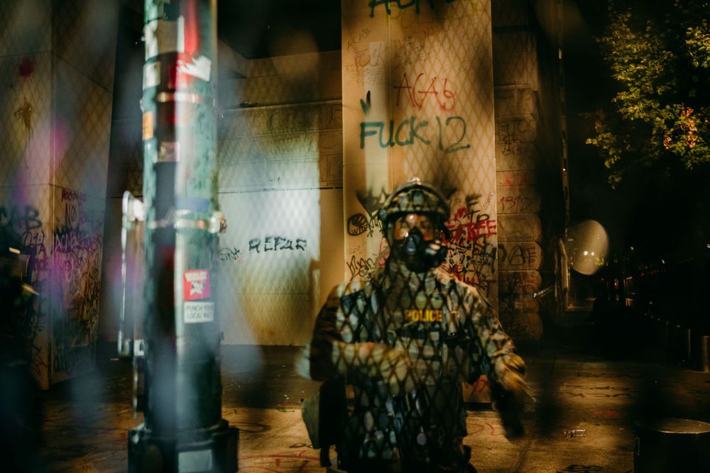 blurry image of police officer through fence blm protests portland oregon photojournalist photojournalism