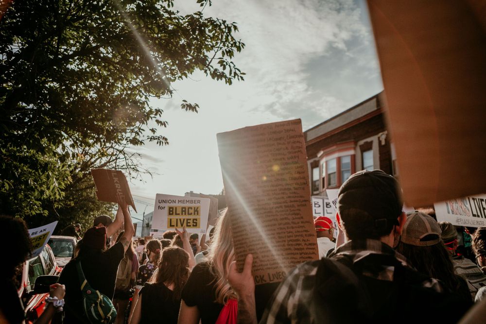 sun shining in sea of blm protest signs portland oregon photojournalist kimberly marie kimble