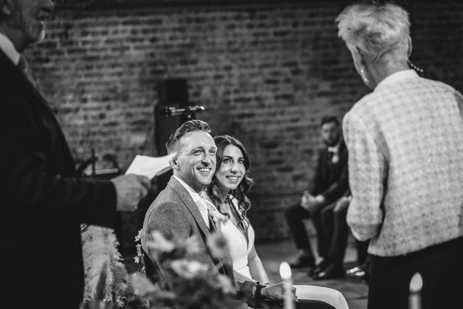 Wedding celebration captured in black and white at a brick-walled venue.