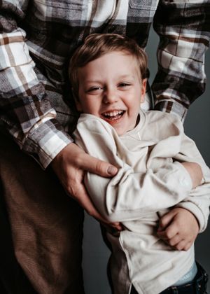 Young child in white hoodie smiling while being held.
