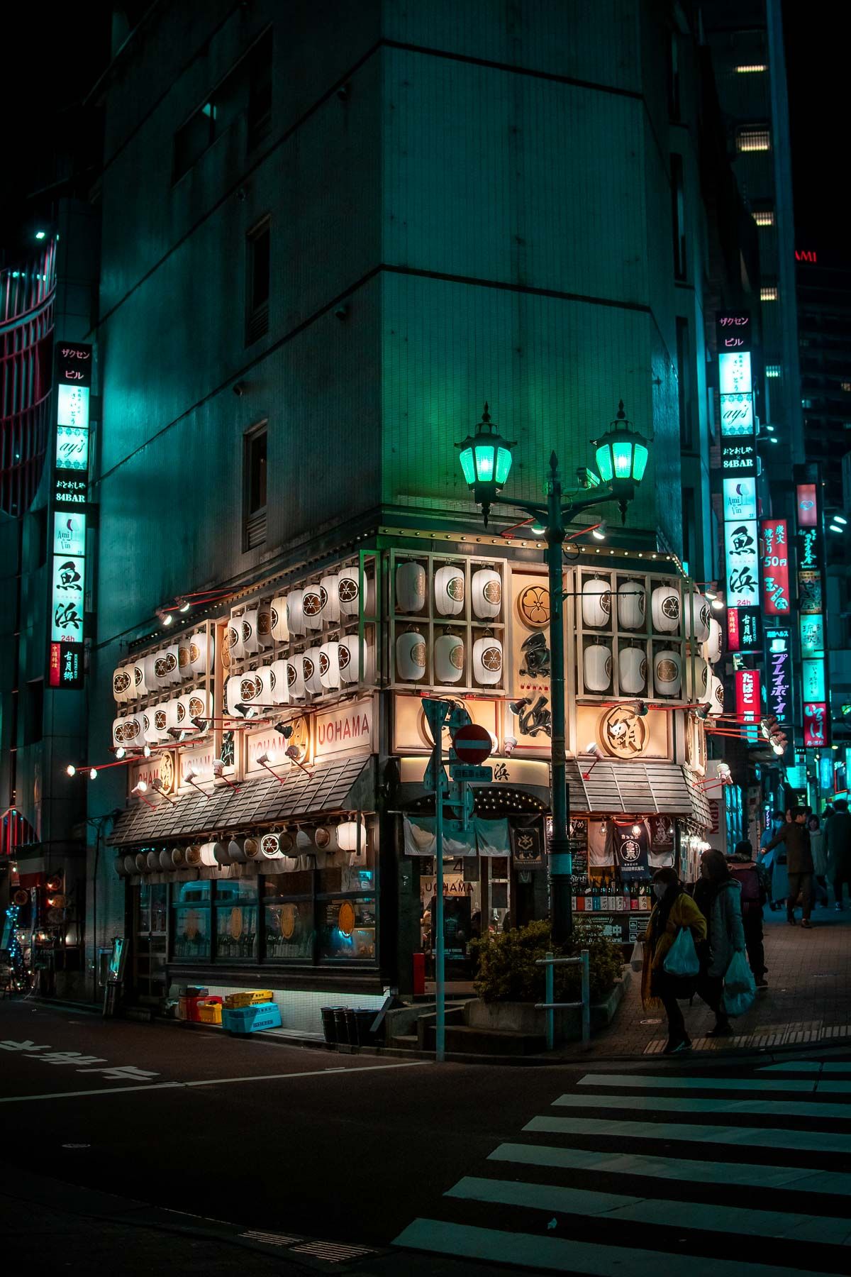 Corner building in Tokyo with illuminated lanterns and traditional Japanese architecture at night.
