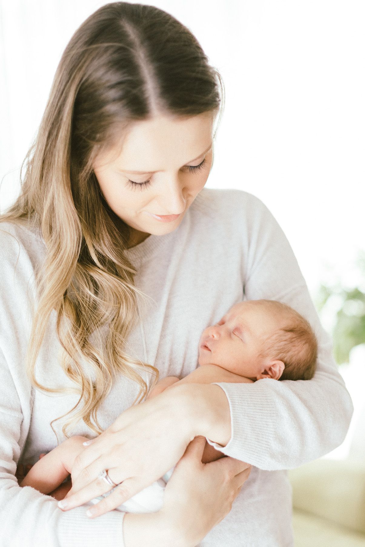 Intimate nurturing moment between parent and newborn in soft natural lighting.