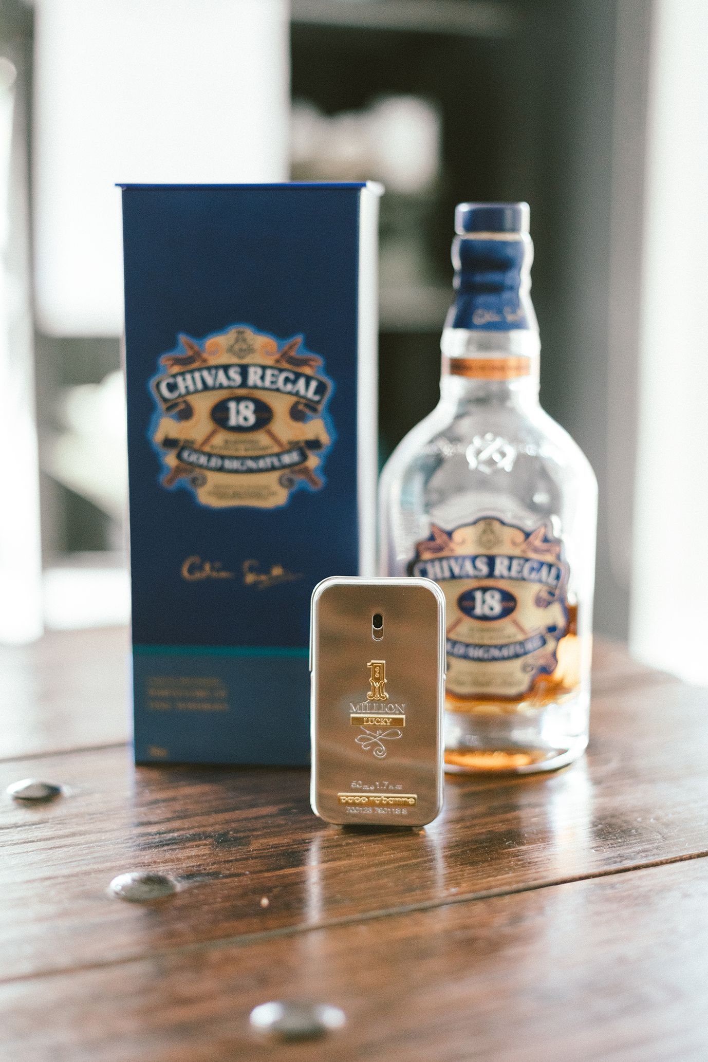Chivas Regal 18 whiskey bottle with matching perfume and packaging on wooden table.