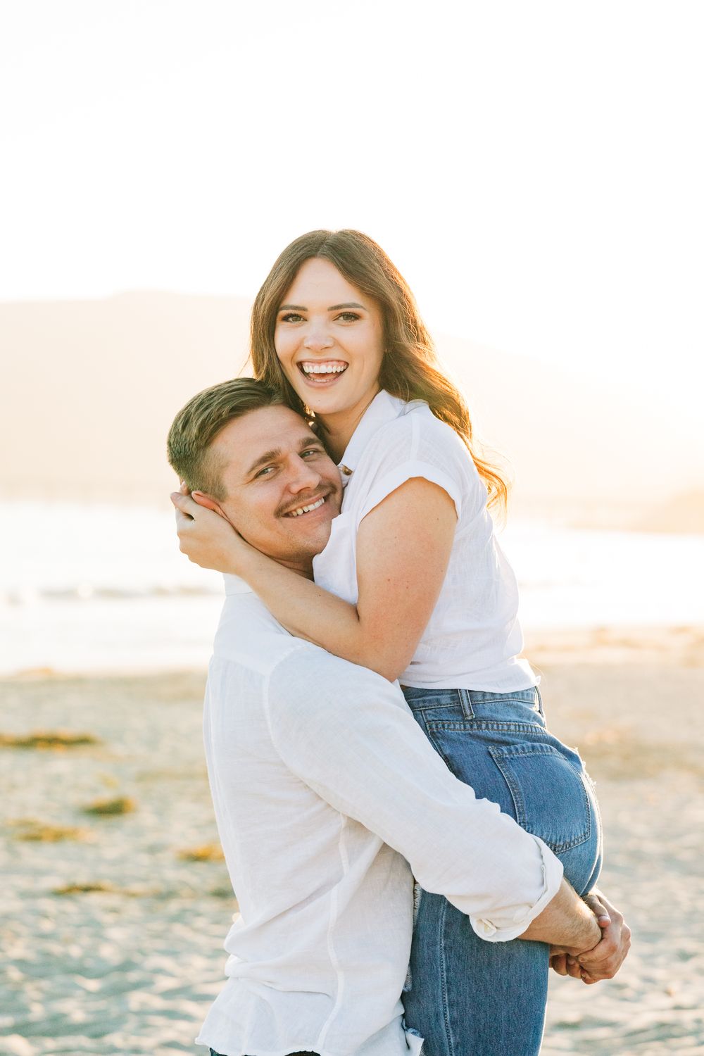 Husband holding his wife on the beach at sunset in Avila Beach, CA