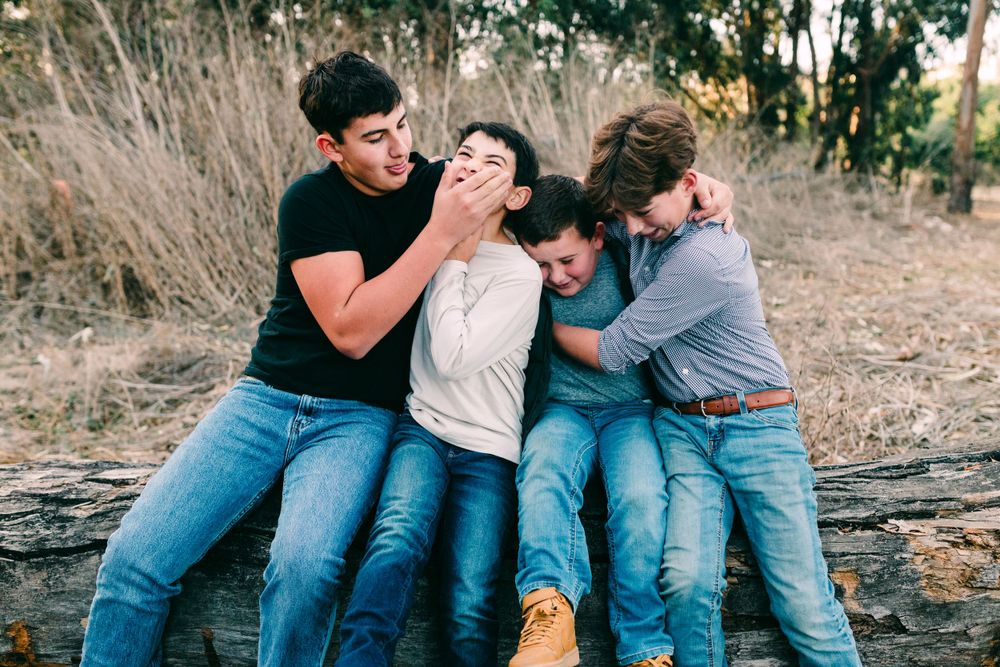 Four brothers sitting on a log playing, Santa Maria, CA