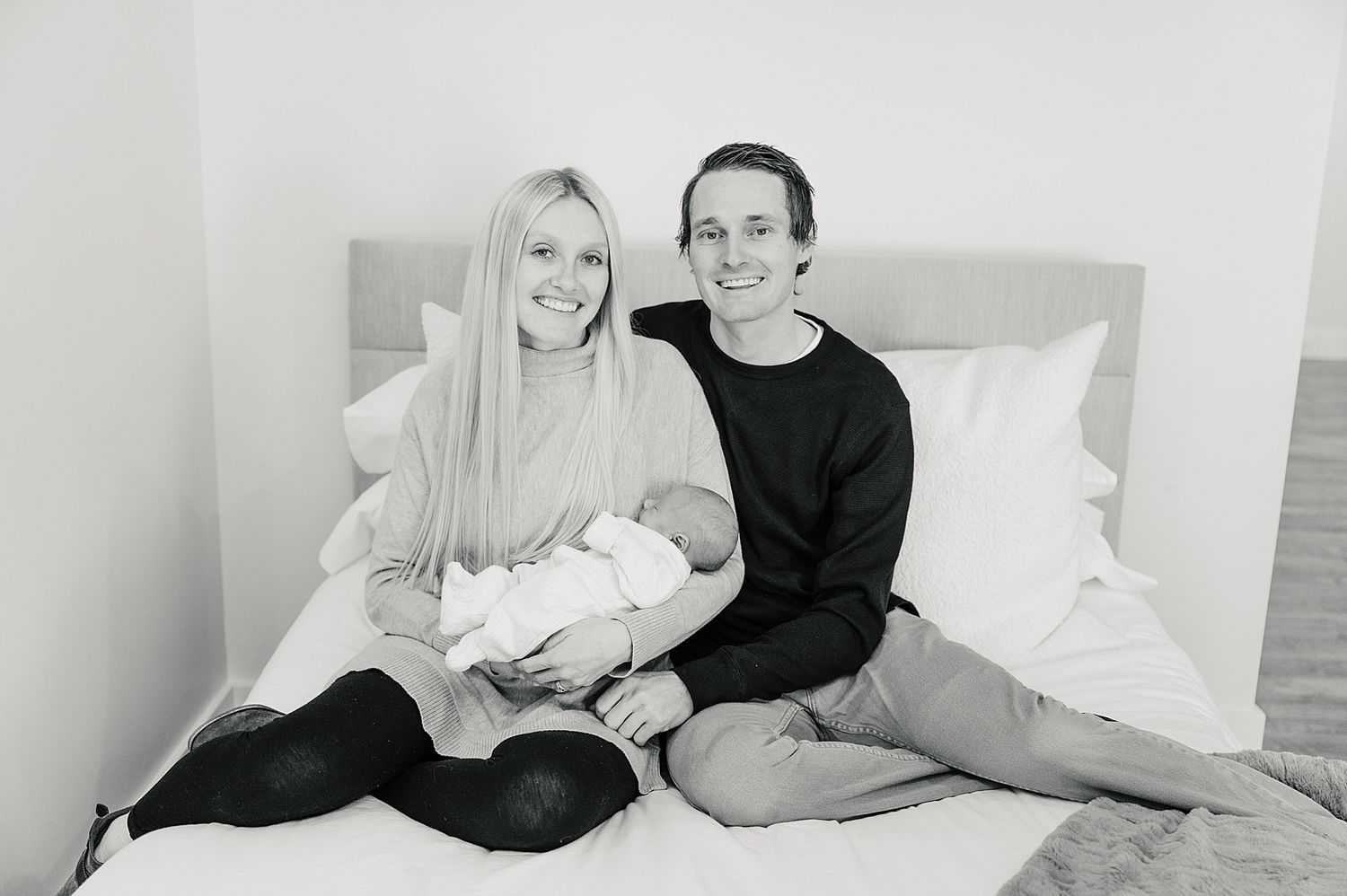 Black and white portrait of three people relaxing together on a bed.