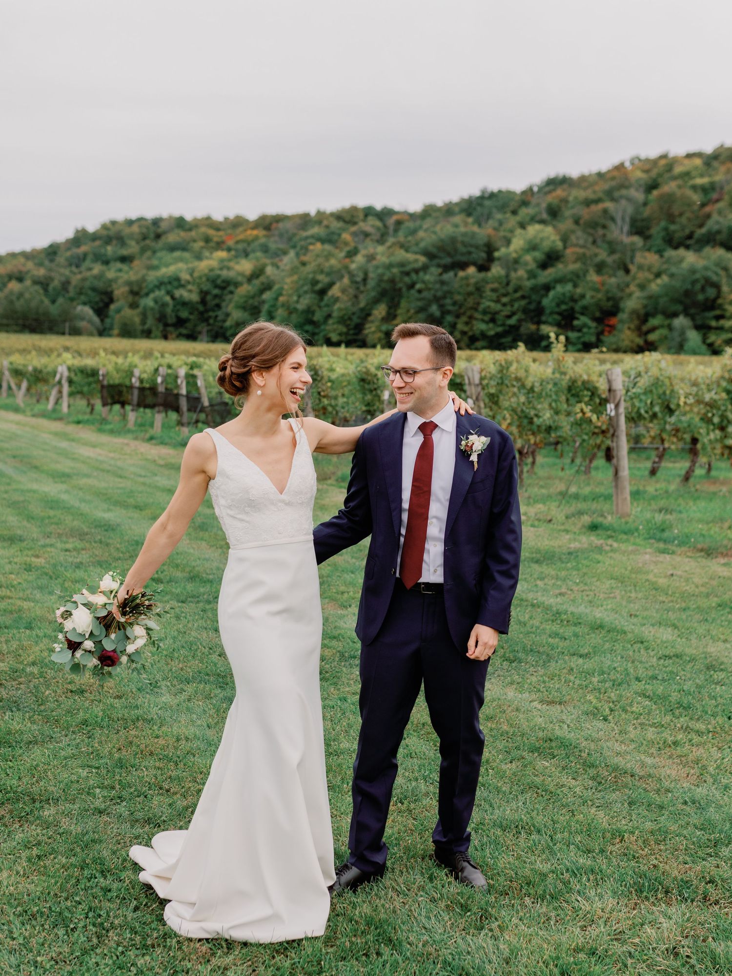 A Candid Moment captured by Katie Crane Photography of a bride and groom holding hands in Cave Springs Winery's vineyard
