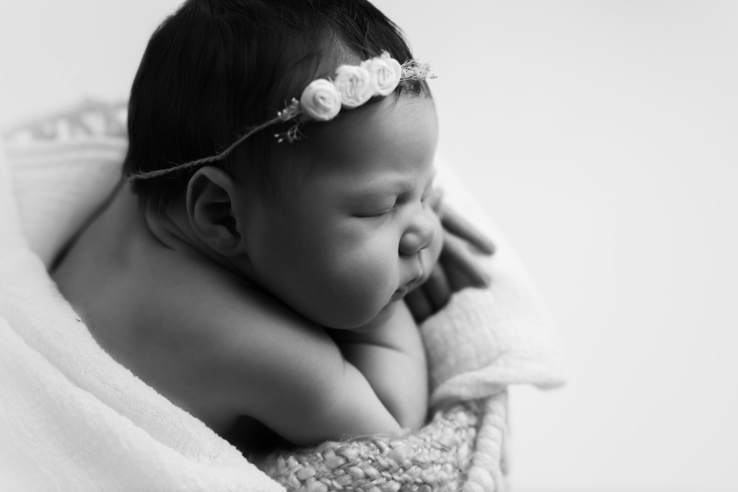 Black and white image on newborn baby girl.  Close up on her face and cheek.