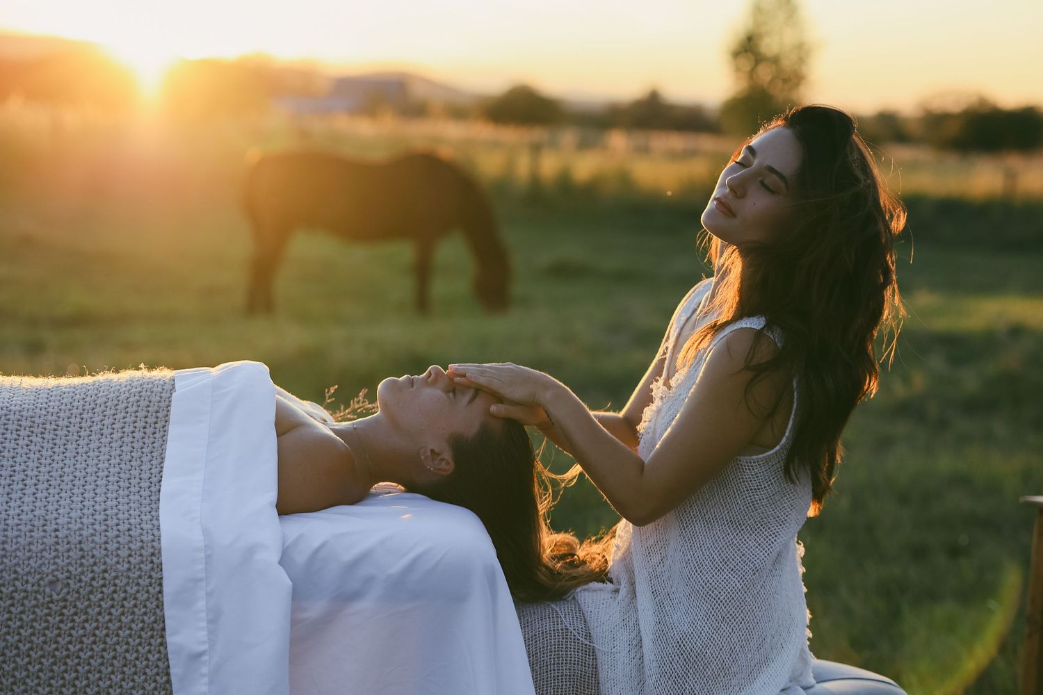 a peaceful facial in a beautiful Montana field at sunset with horses roaming free