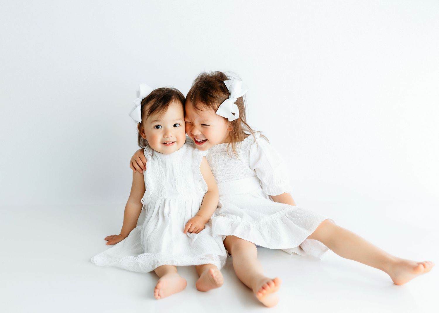 A toddler sister hugging on a white backdrop. Greenville, SC newborn photographer, Easley, SC Newborn photographer