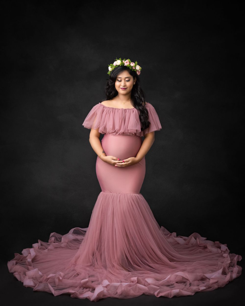 Maternity portrait in pink mermaid gown with floral crown and dramatic tulle train.