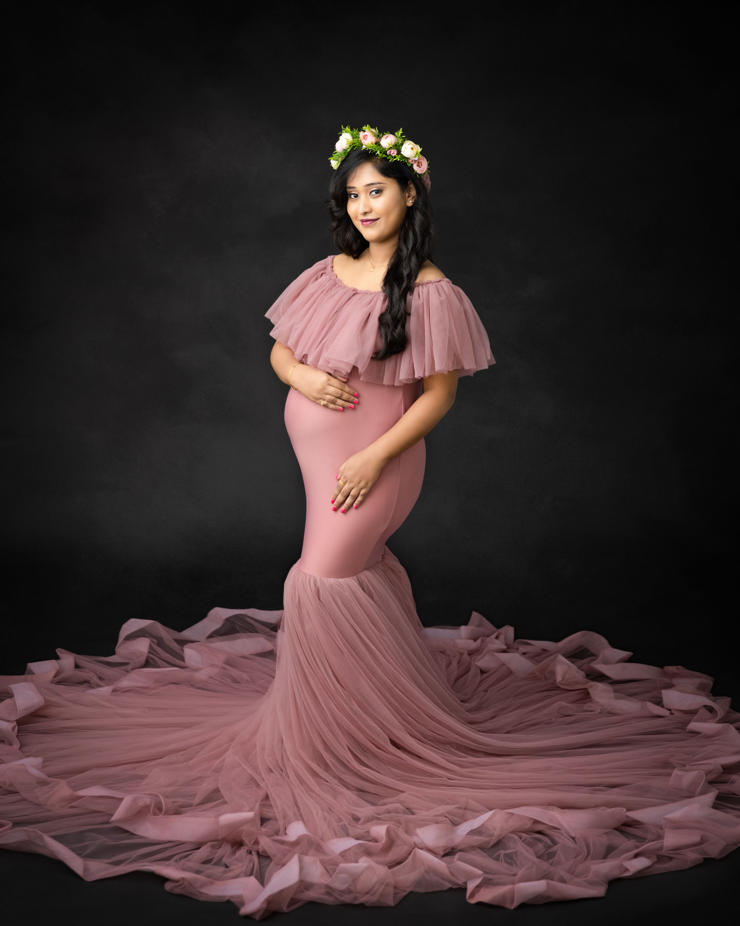 Ethereal maternity portrait in pink mermaid dress with floral crown and dramatic tulle train.