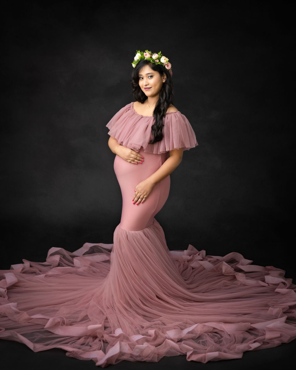 Ethereal maternity portrait in pink mermaid dress with floral crown and dramatic tulle train.