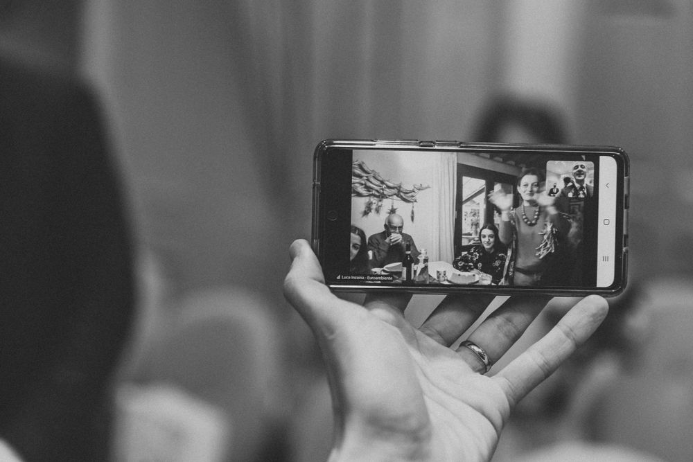 Hand holding phone capturing wedding ceremony on video in black and white.