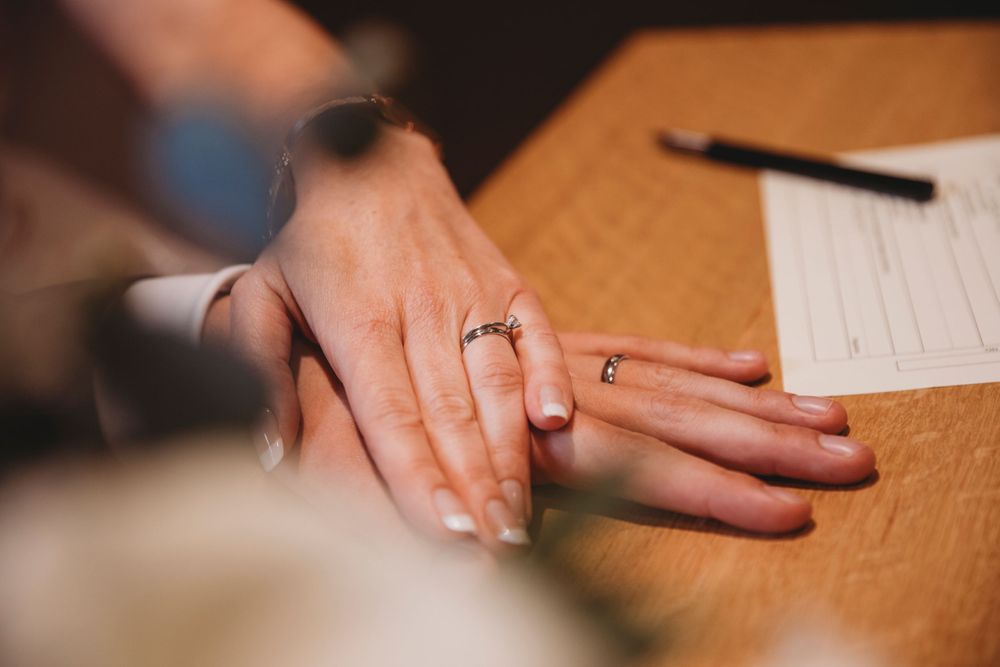 Close-up photo of engagement ring on hand with document in background.