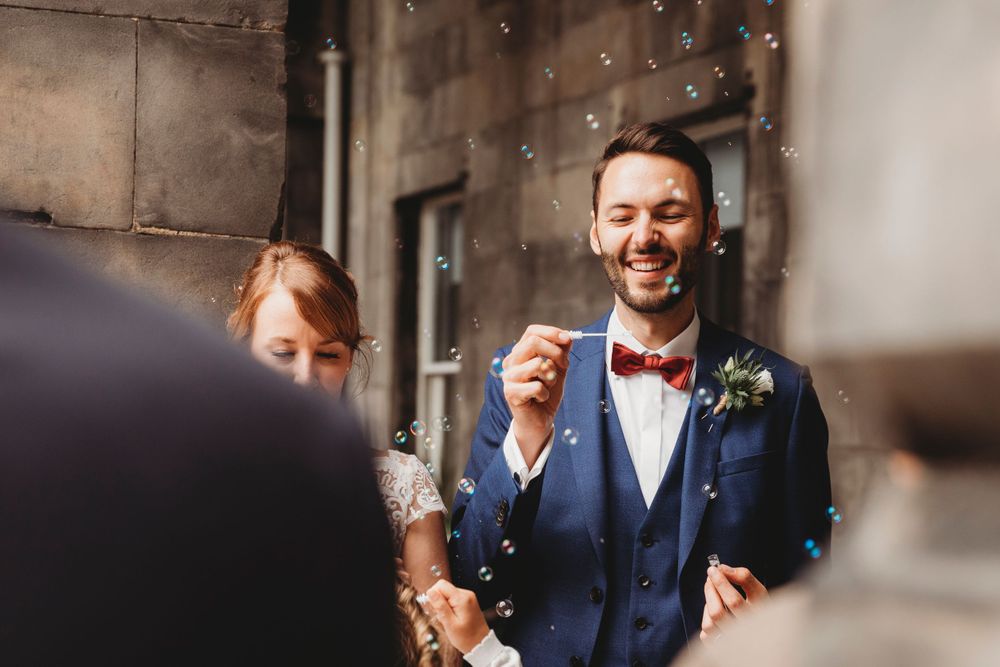 A joyful moment captured during a wedding celebration with bubbles floating in the air.