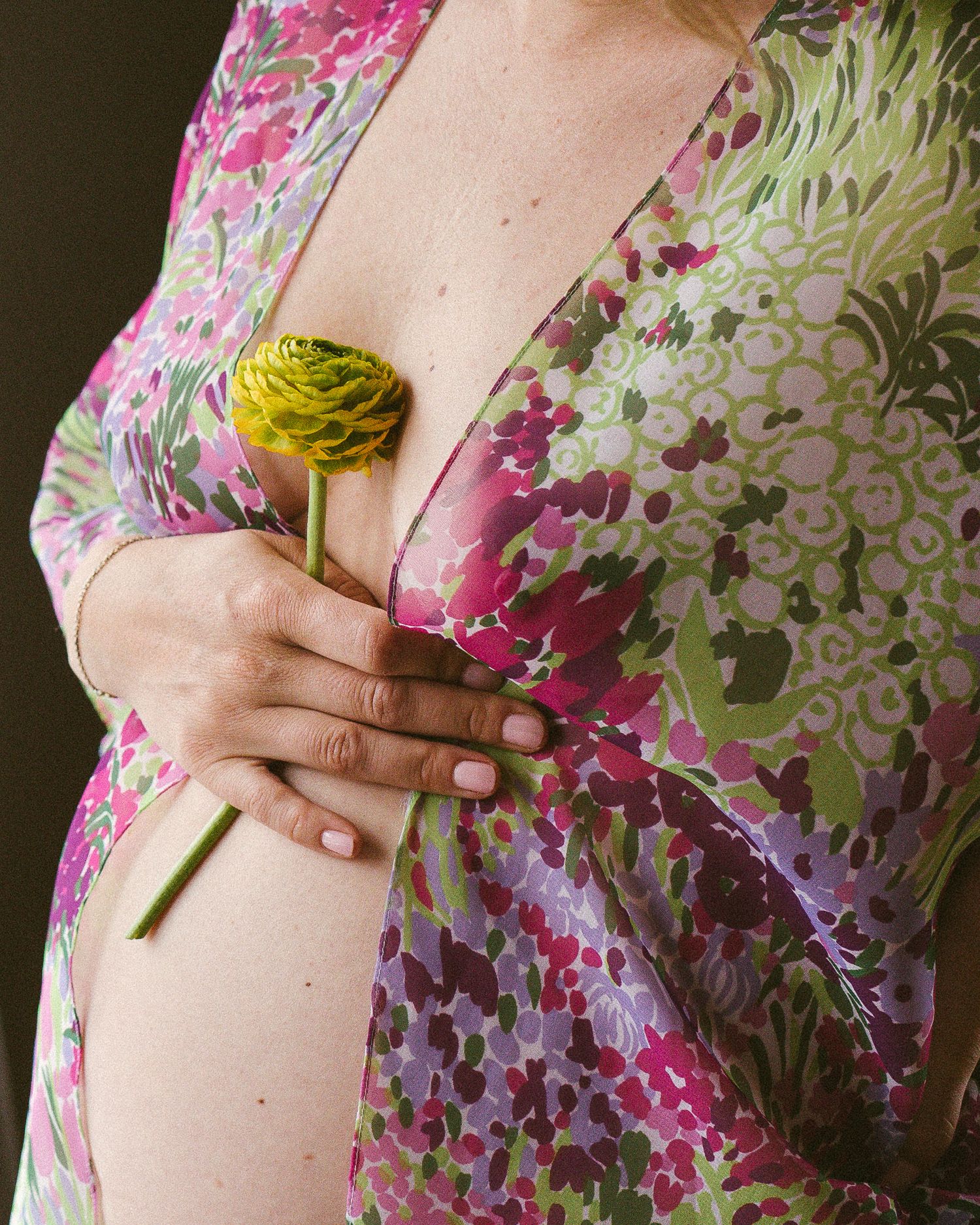 Close-up of a pregnant woman holding hand with a flower on naked belly