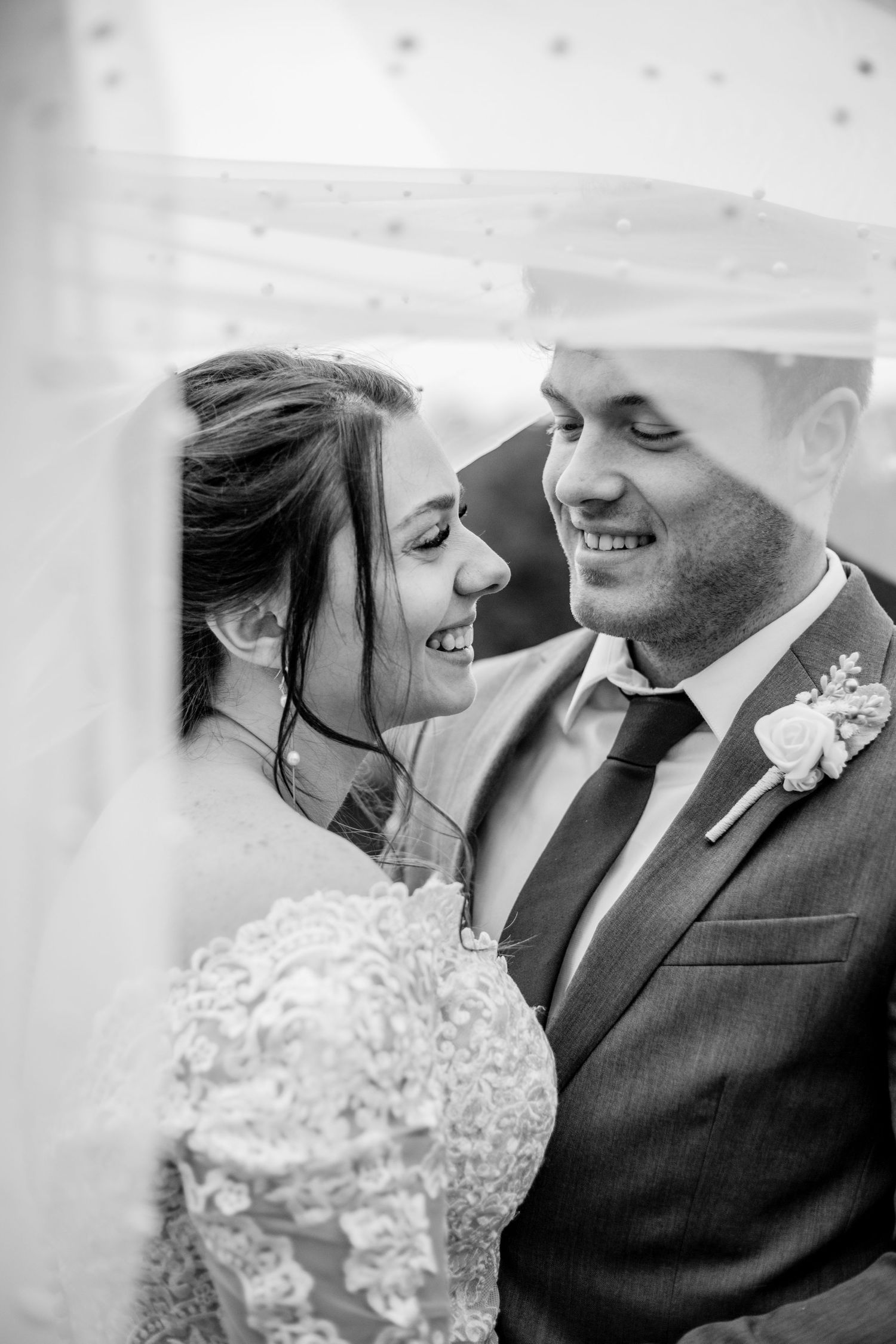 A romantic black and white moment shared between newlyweds under a delicate veil.