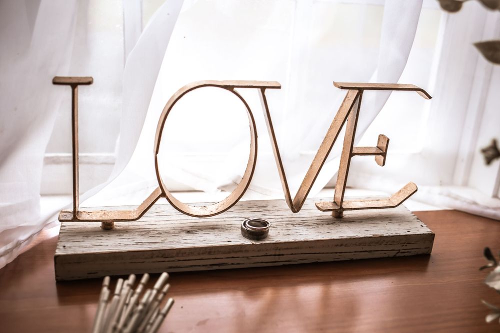 Wooden LOVE sign decoration displayed on rustic surface with white fabric backdrop.
