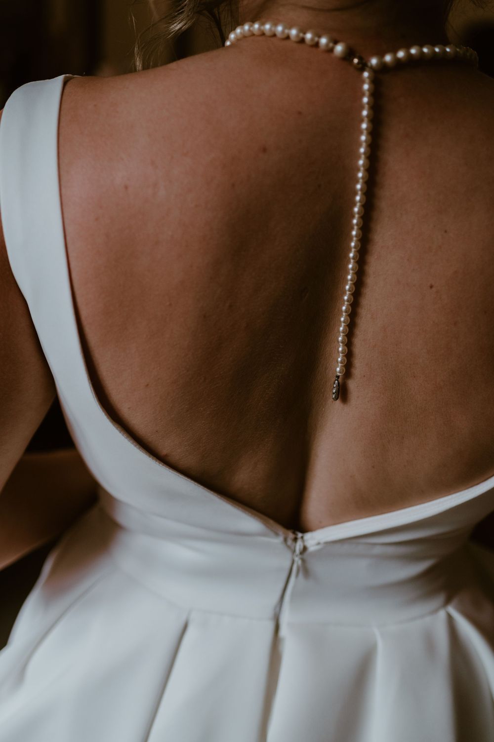A close up photo of the brides back with her wedding dress and necklace on at Hareston Manor
