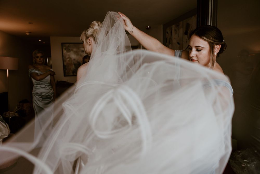 A bridesmaid tossing the veil with the bride at Sandy Cove Hotel