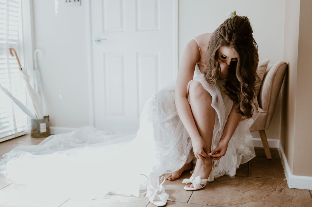 Bride putting her wedding shoes on at Beaconside House