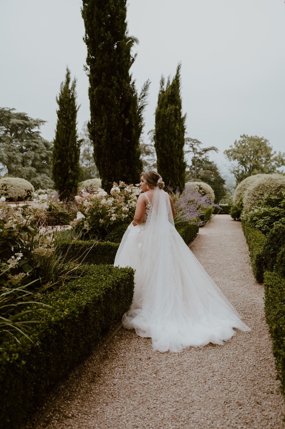 A bride walking through the gardens in her wedding dress at Deer Park Country House