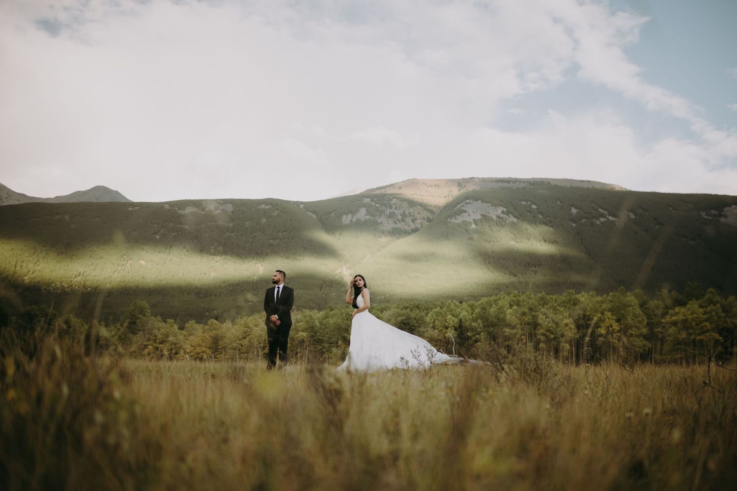 Couple standing in misty mountain meadow for wedding photos.