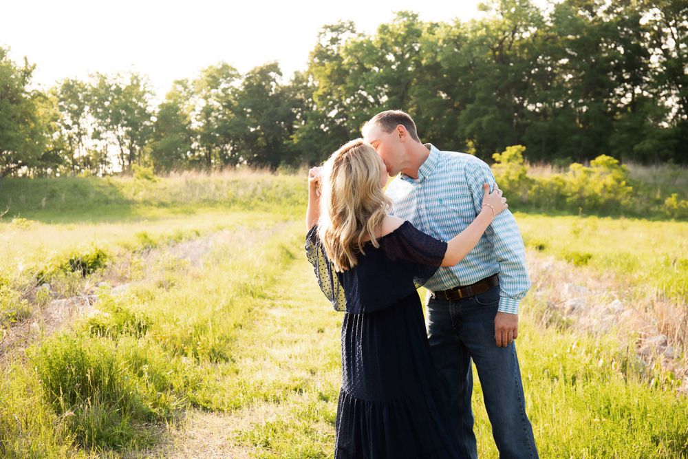 A tender moment between a couple in a sun-drenched field with wildflowers.