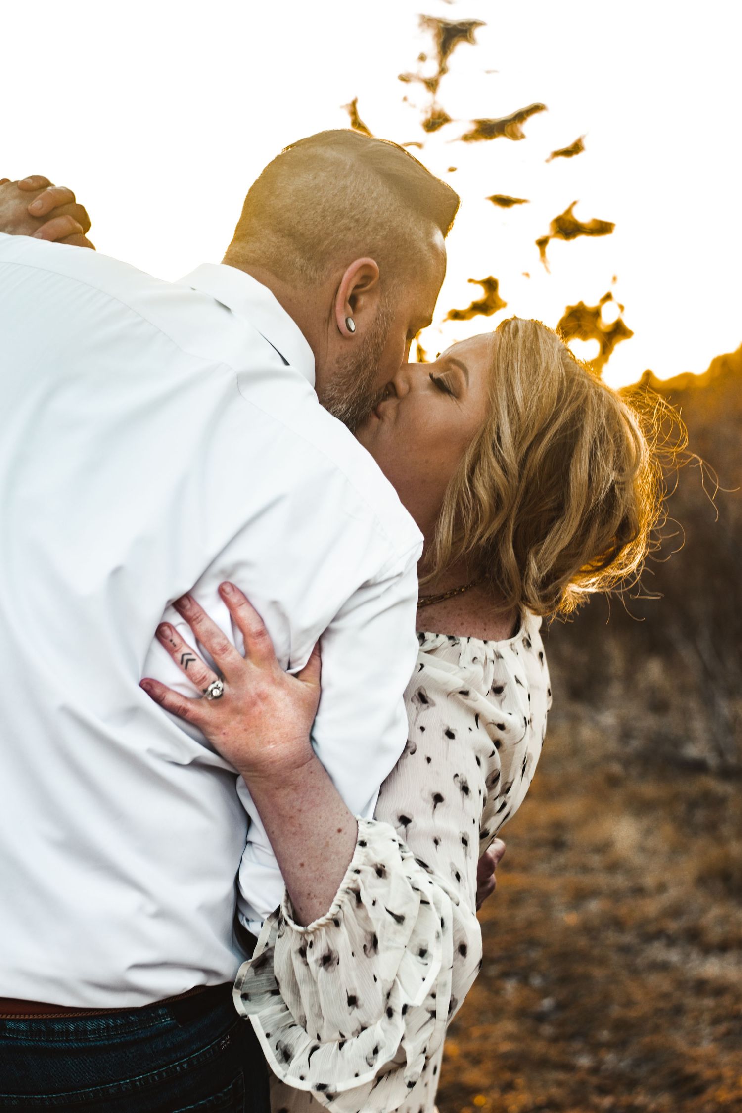 A romantic couple shares an intimate kiss at sunset with golden birds flying overhead.
