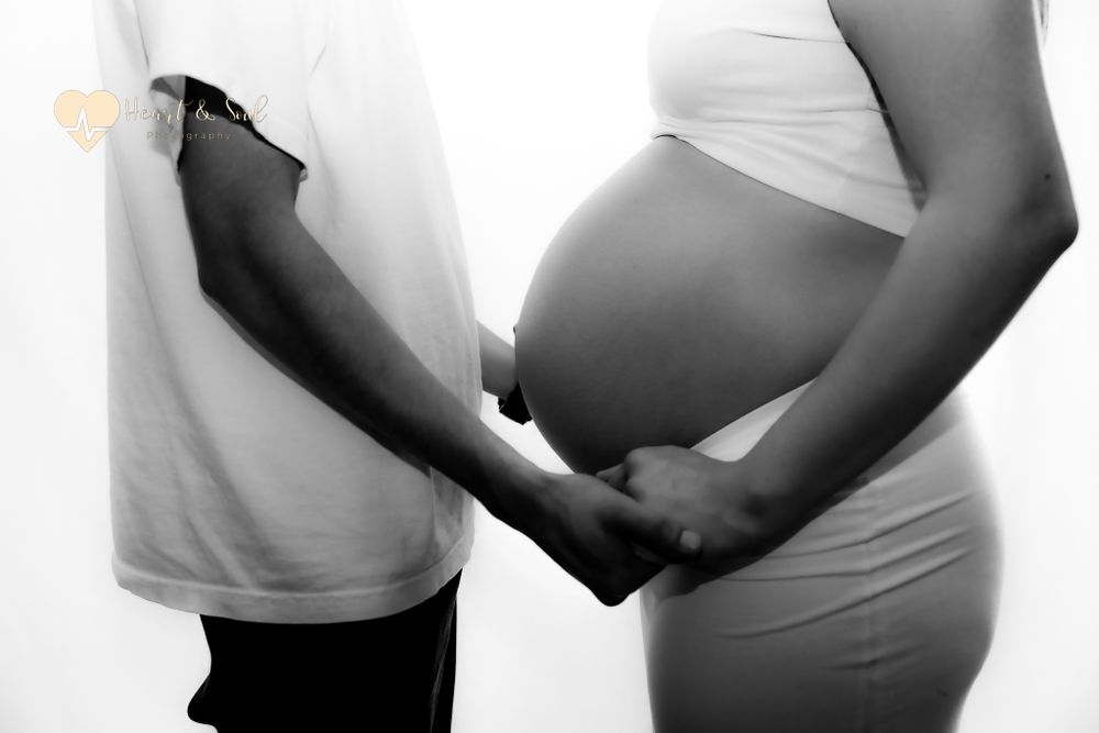 black and white pregnant baby bump and hands holding