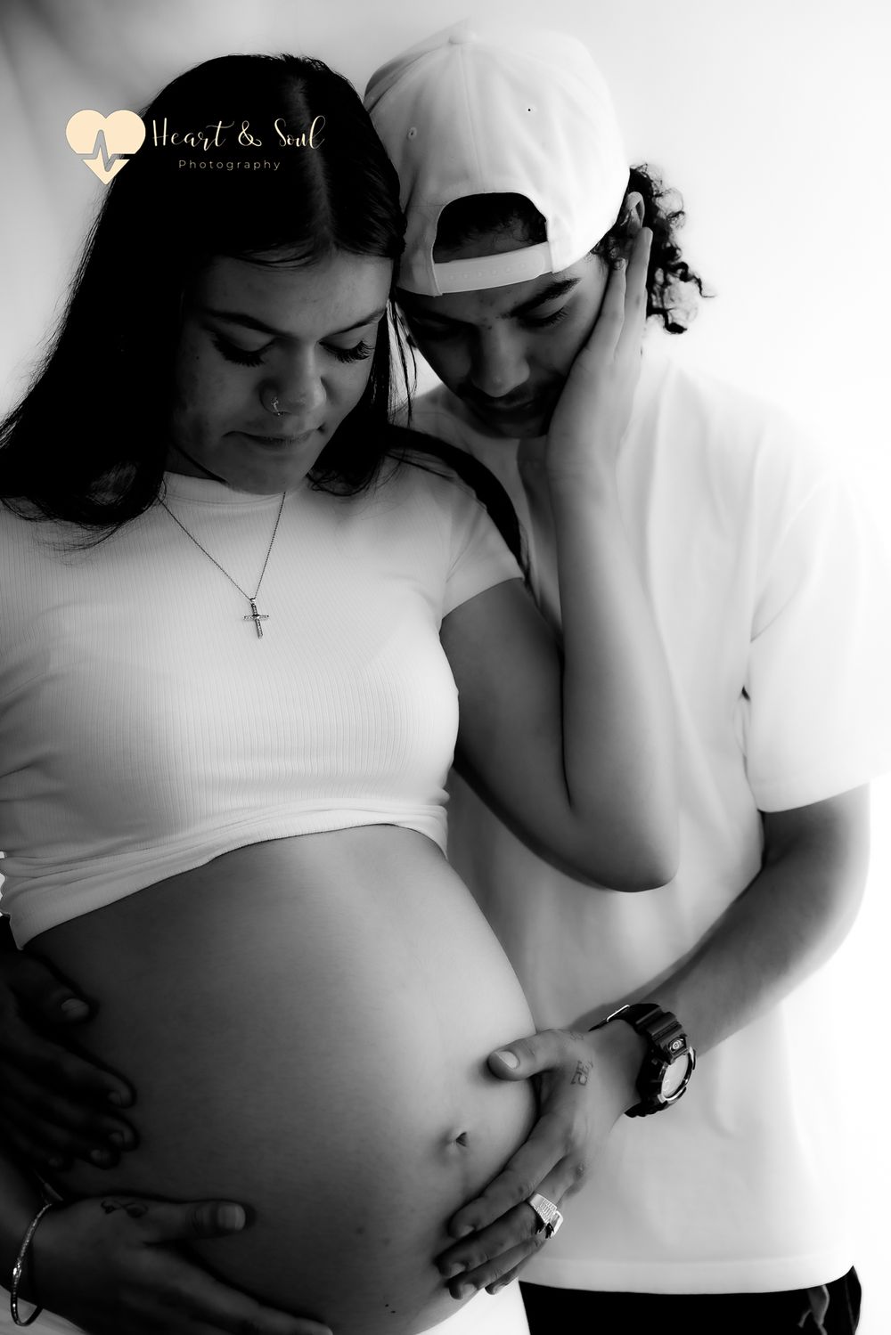 black and white photo of lady and man holding pregnant baby bump