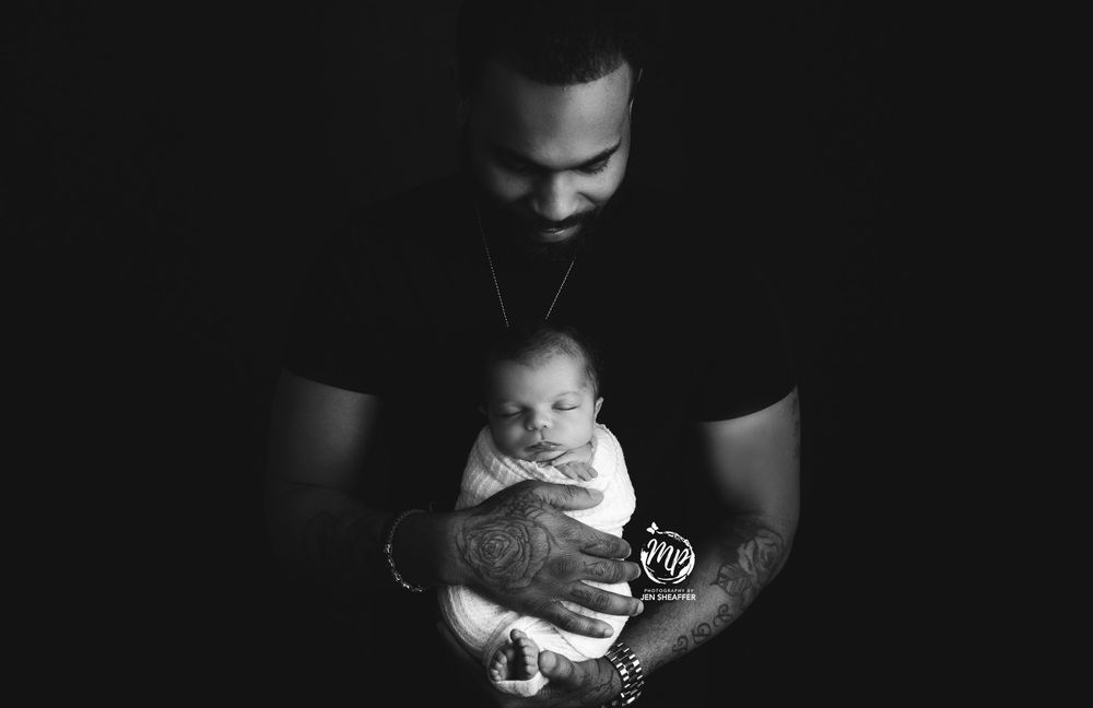 Dad's strong arms tattoo holding his baby