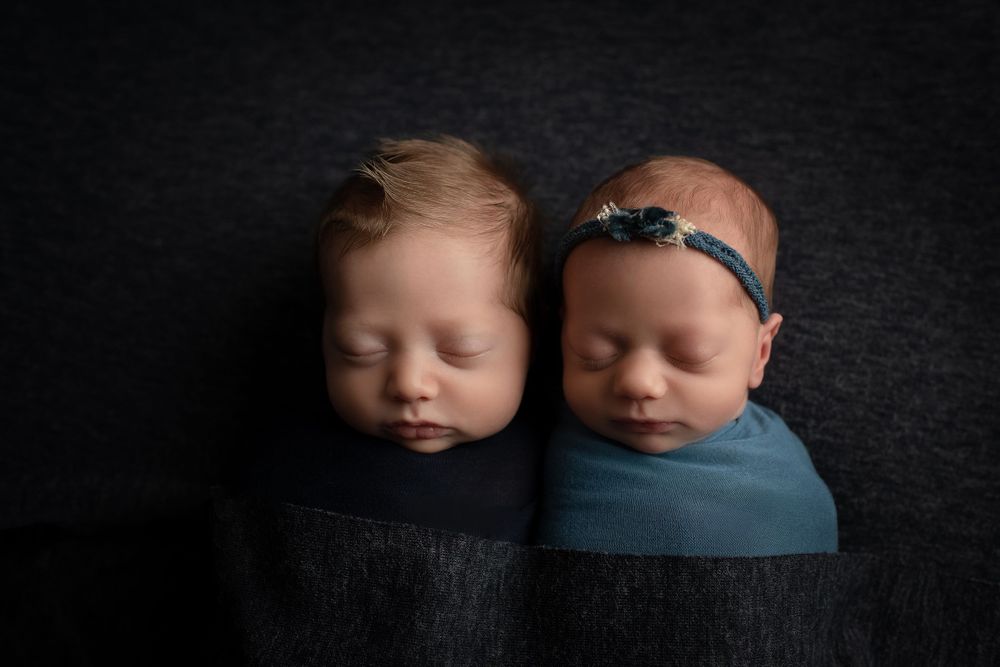 Twin newborns in blue wraps boy and girl