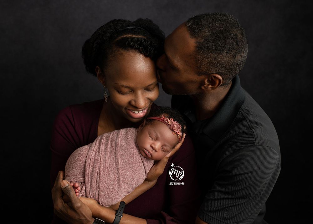 parents holding newborn and dad kissing mom