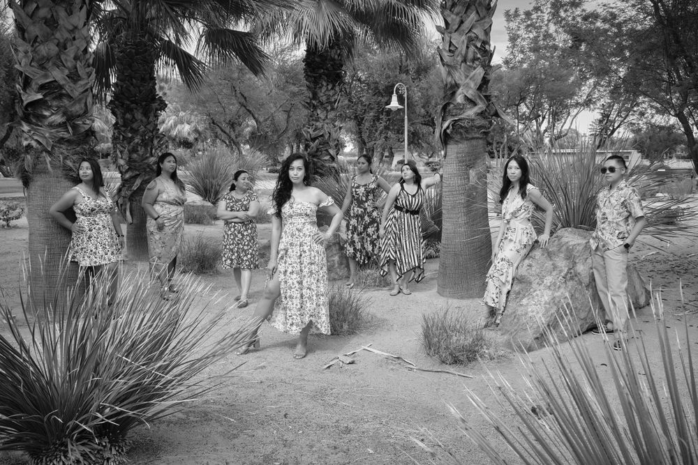 A group dancing in a desert garden setting wearing floral dresses in black and white.