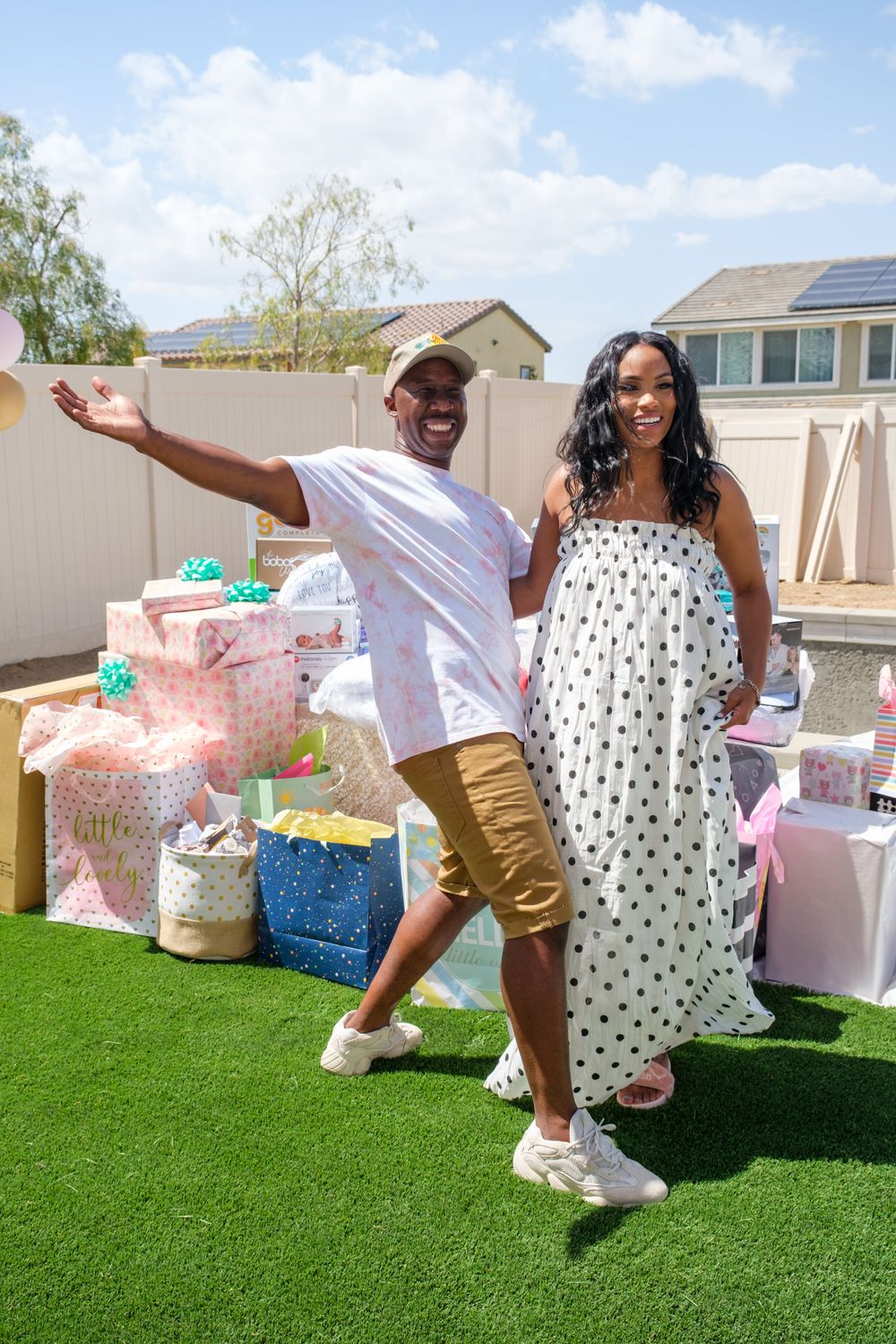 Outdoor party setup with pink decorations and wrapped gifts on artificial grass.