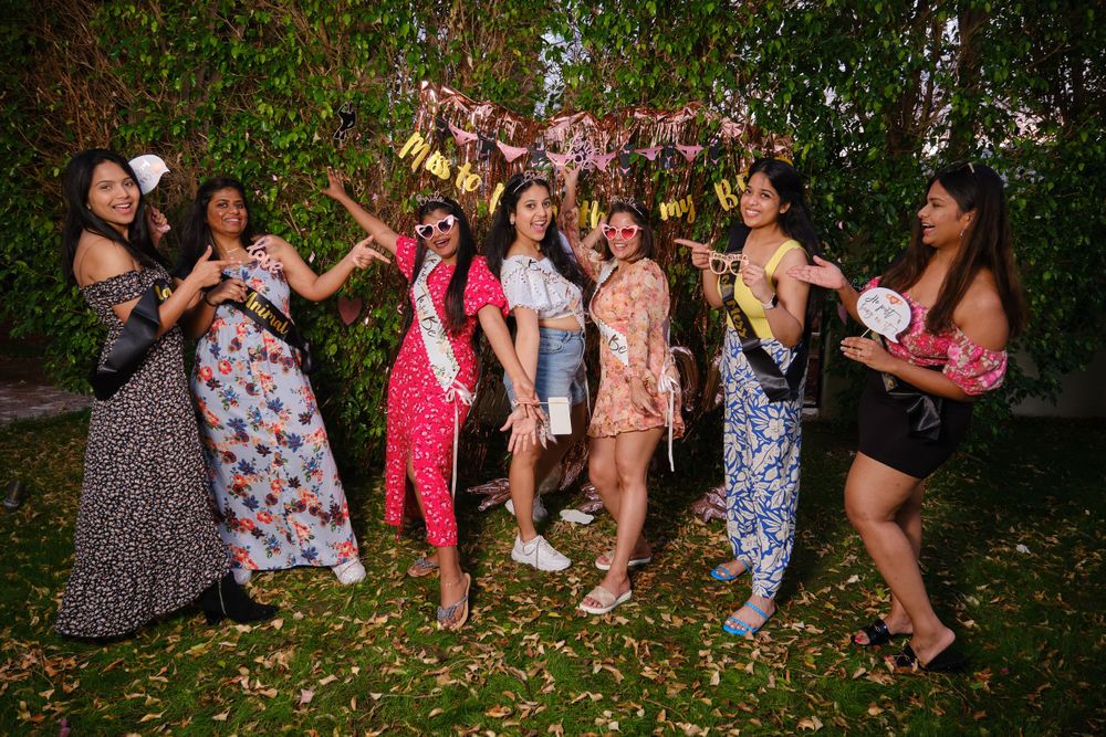 Friends in floral dresses celebrate outdoors with joyful poses and laughter.