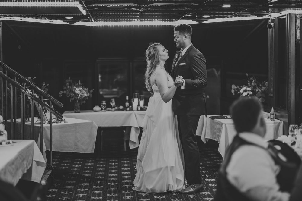 Black and white photo of bride and groom sharing their first dance at wedding reception.