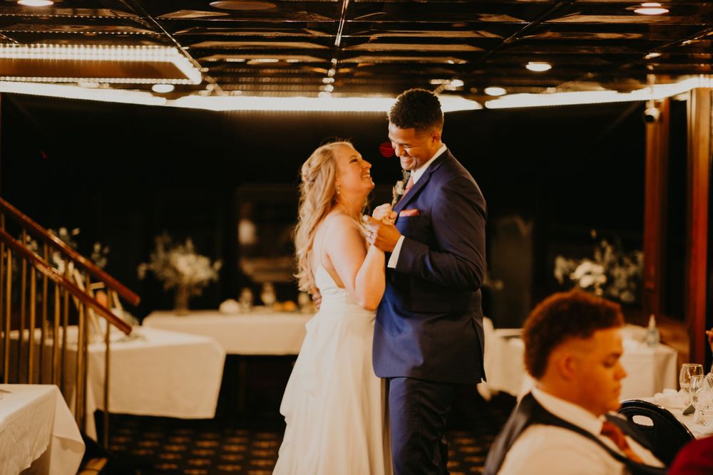 Couple sharing intimate first dance bathed in warm golden light at wedding reception.