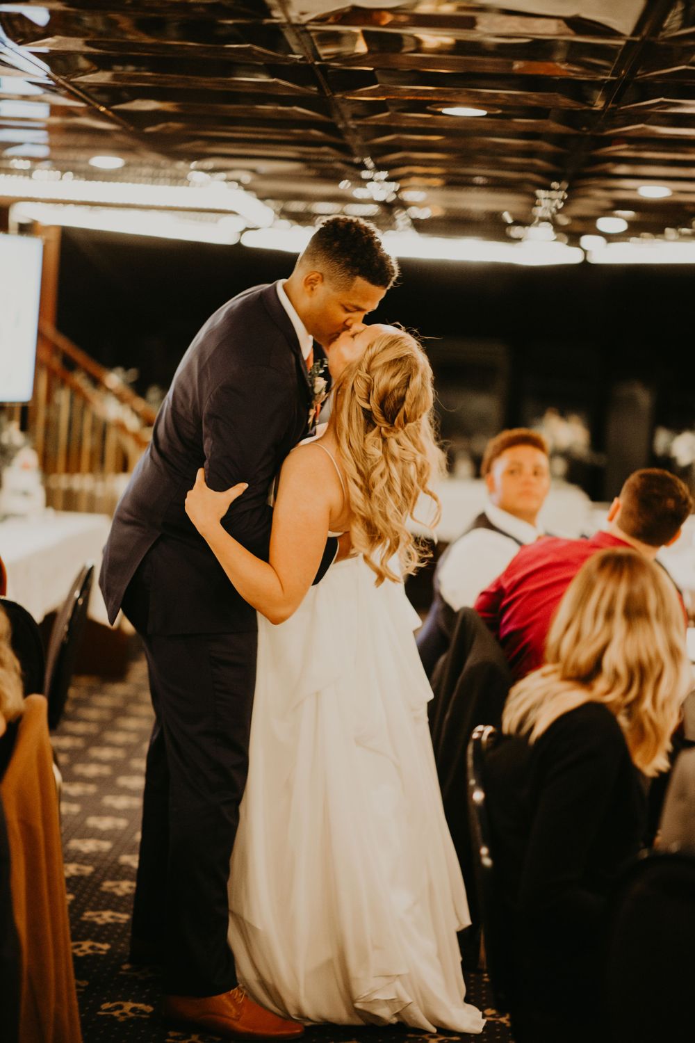 Bride and groom sharing a passionate kiss on the dance floor at wedding reception.