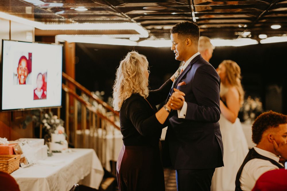 Groom dancing with mother while bride dances with father at wedding reception.