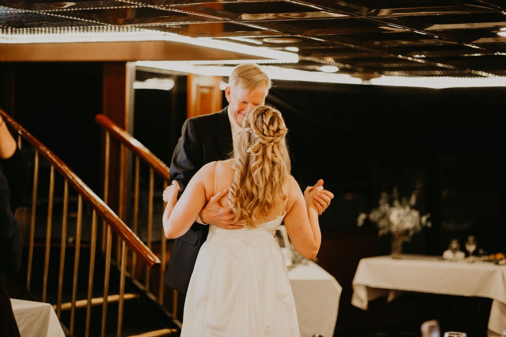Bride and groom share an intimate first dance at their wedding reception near a wooden staircase.