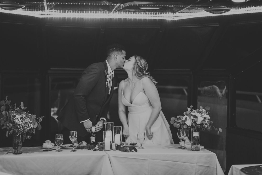 Black and white photo of bride and groom sharing a romantic kiss at the sweetheart table.