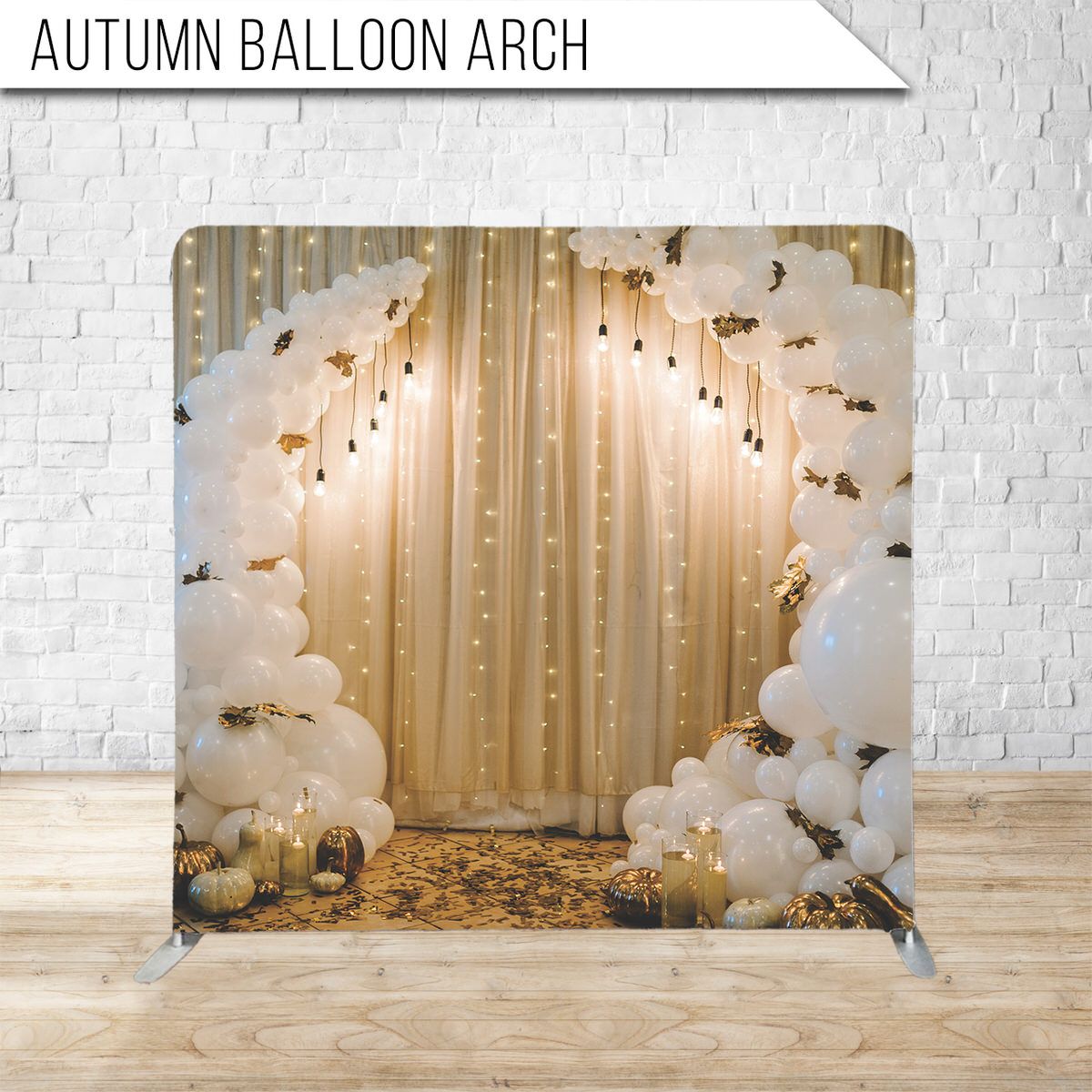 White balloon arch with floral accents against a gold curtain backdrop creates an elegant event display.