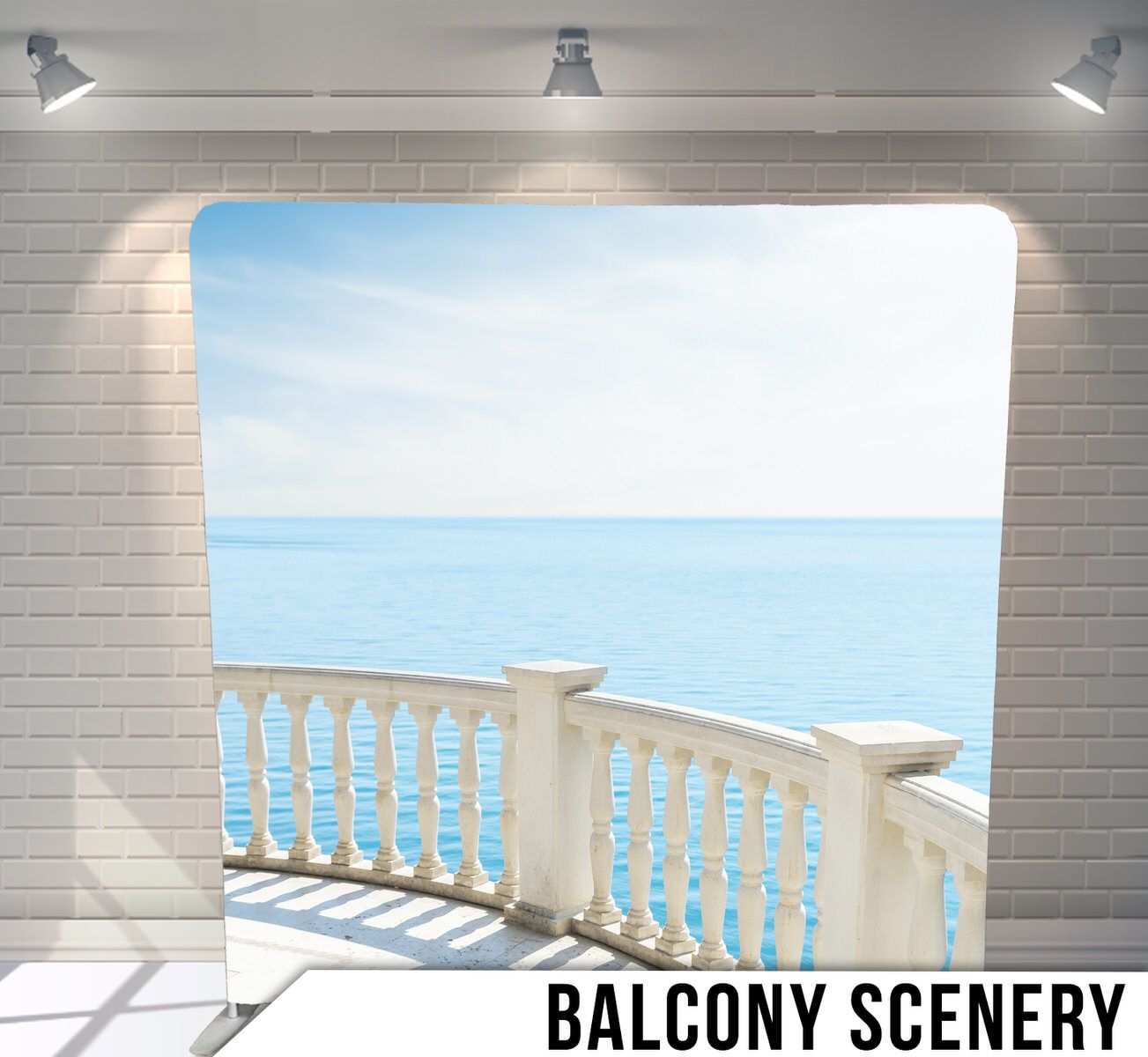A white balcony with ornate railings overlooking a serene ocean view with blue waters stretching to the horizon.