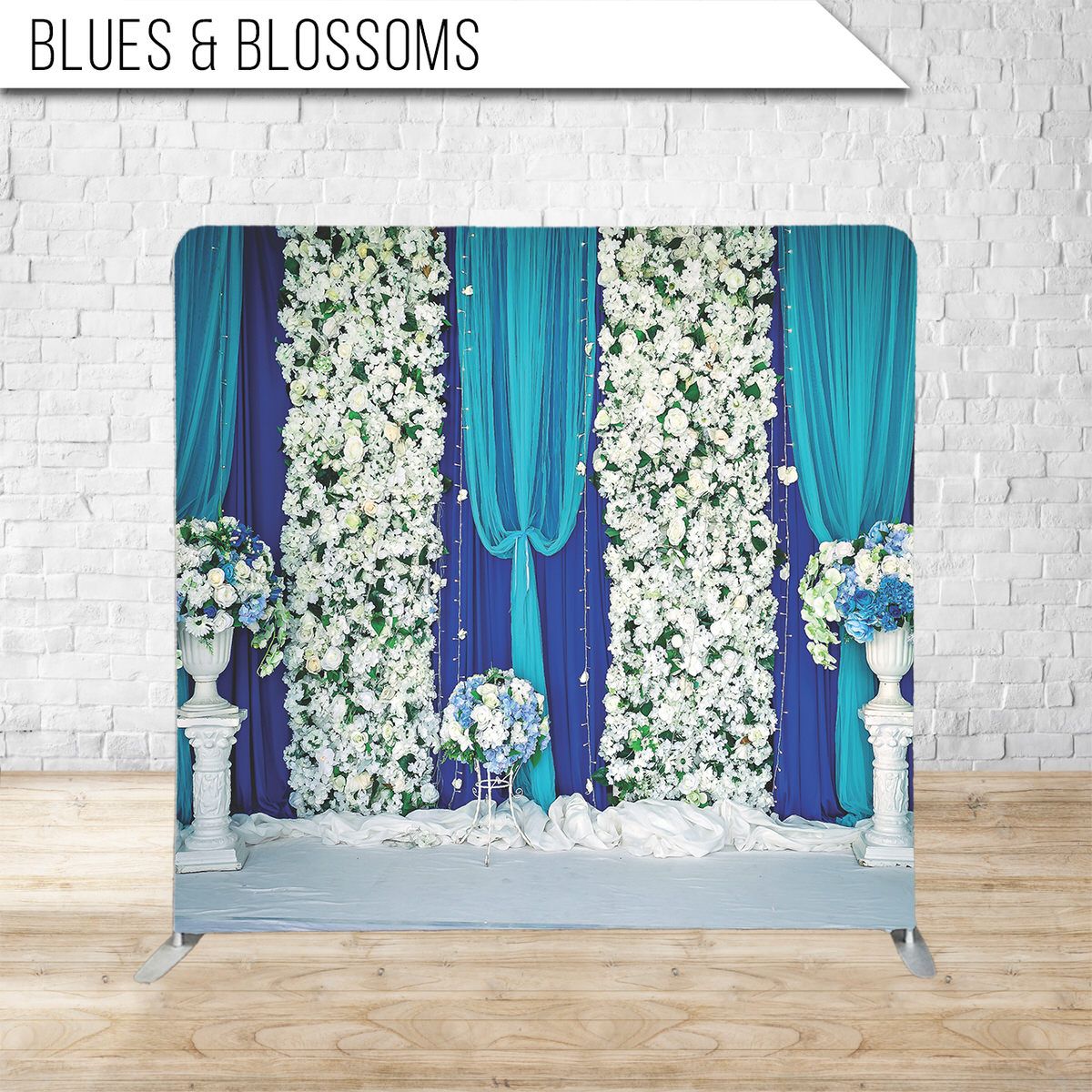 Elegant wedding backdrop with white floral arrangements and blue drapery.