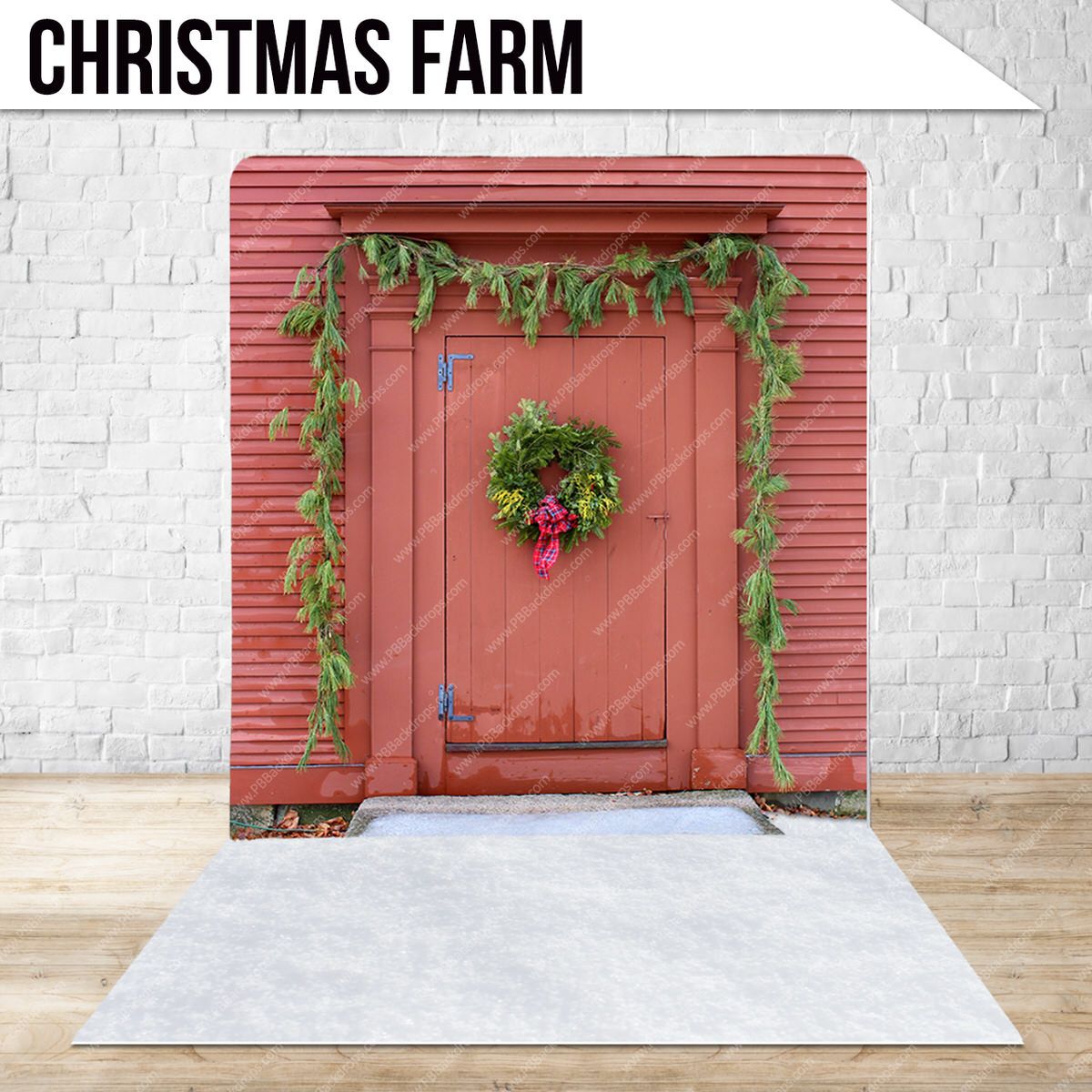 Red rustic door decorated with Christmas wreath and garland against white brick wall.