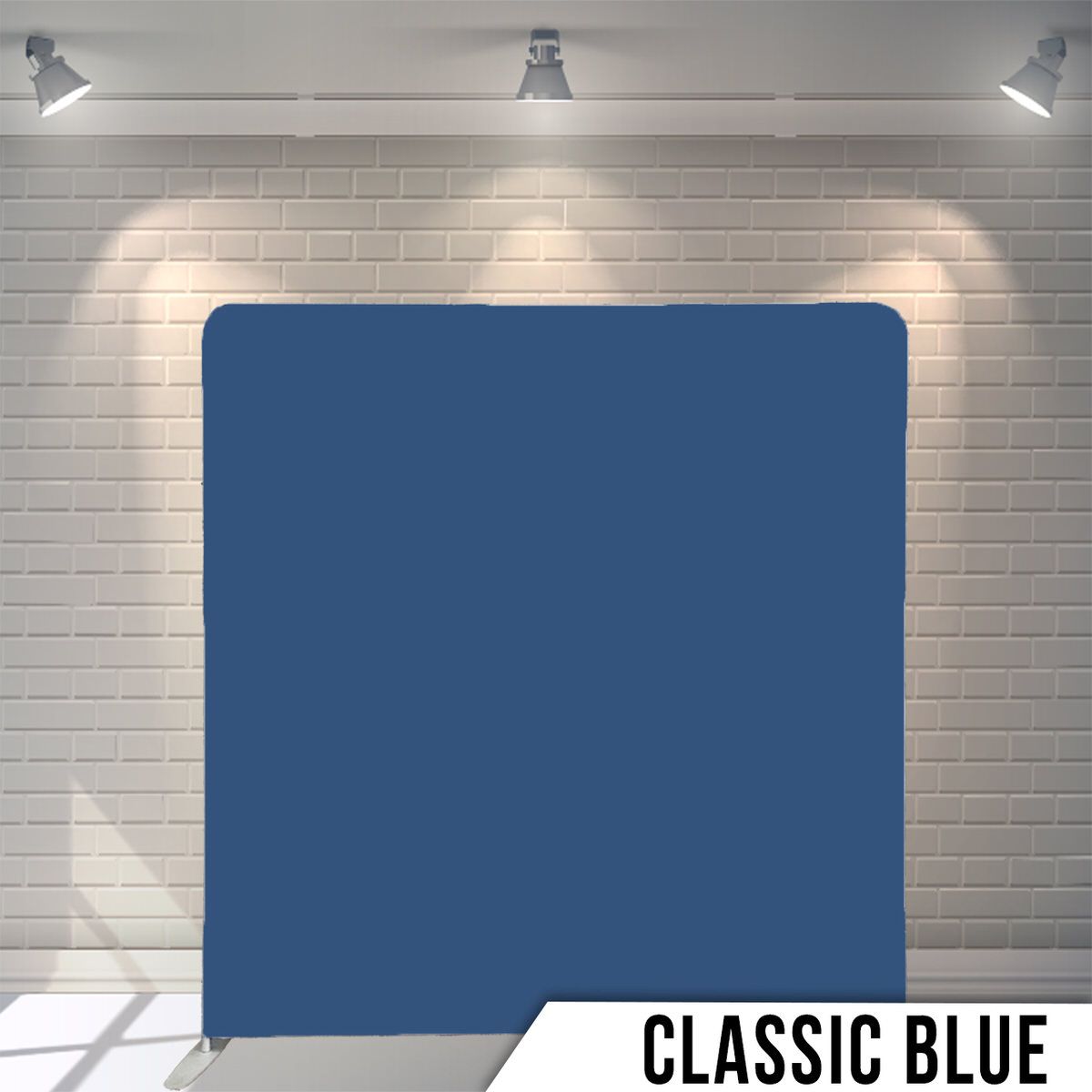 Solid classic blue photography backdrop against white brick wall with studio lighting.